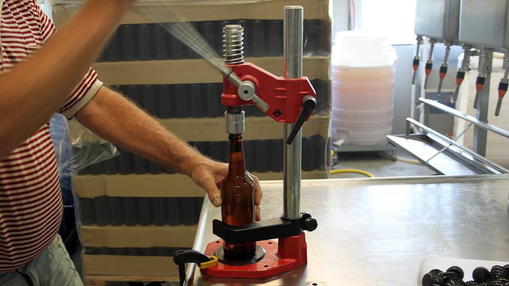 A beer cap is being placed manually
